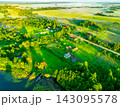 Aerial view of rural village nestled in lush green fields and forests at sunrise with mist hovering  143095578