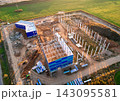 Aerial view of industrial construction site with steel frame and blue modular buildings 143095581