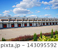 Large industrial warehouse with red loading docks under blue sky with white clouds 143095592