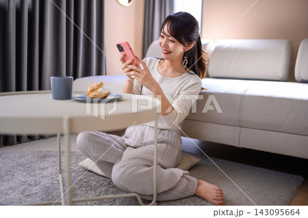 床に座りスマホでシュークリームを撮る女性 143095664