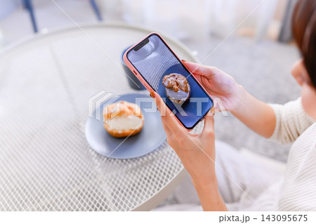 スマートフォンでシュークリームを撮影する女性の手元 スマートフォンでシュークリームを撮影する女性の手元 143095675