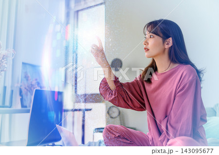ベッドでノートパソコンを使いながら空間を指差して考える女性 ベッドでノートパソコンを使いながら空間を指差して考える女性 143095677