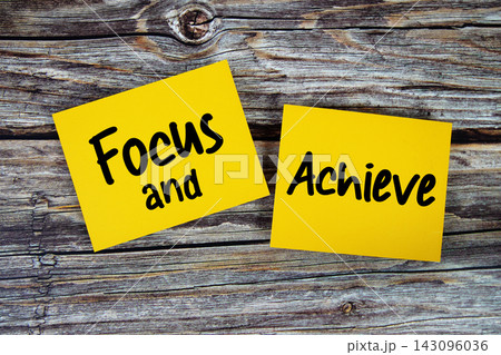 Focus and Achieve text written on paper notes top view on wooden background 143096036