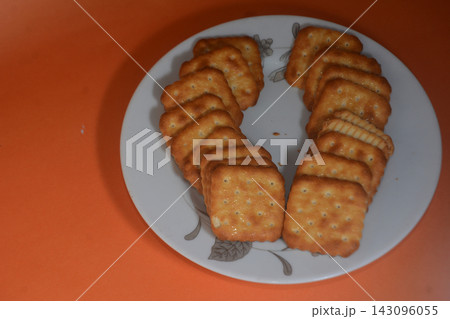 Square crispy crackers arranged in a u-shape on a white plate with floral patter Square crispy crackers arranged in a u-shape on a white plate with floral patter 143096055