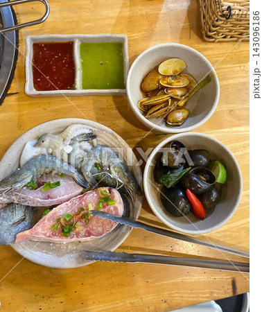 Raw seafood platter with shellfish, dipping sauces, herbs, and lime on wooden table Raw seafood platter with shellfish, dipping sauces, herbs, and lime on wooden table 143096186