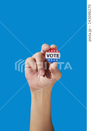 a man holds a vote badge between his fingers 143096270