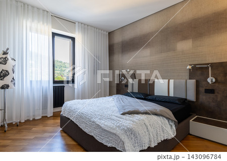 Contemporary Italian bedroom with upholstered bed and textured wallpaper 143096784