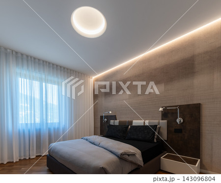 Italian-Designed Bedroom with Illuminated Circular Ceiling Recess and Sheer Curtains Italian-Designed Bedroom with Illuminated Circular Ceiling Recess and Sheer Curtains 143096804