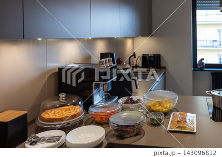 Covered cake and prepared dishes on a kitchen island for informal dinner at home 143096812