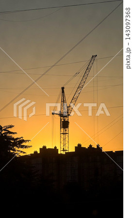 Tower crane silhouette at sunset constructing urban skyline Tower crane silhouette at sunset constructing urban skyline 143097368