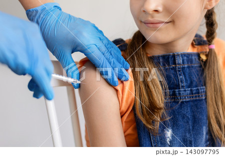 Teen girl receiving vaccine injection in upper arm from healthcare worker Teen girl receiving vaccine injection in upper arm from healthcare worker 143097795
