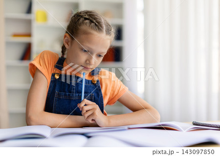 Focused teen girl studying at home with open books and notebook Focused teen girl studying at home with open books and notebook 143097850
