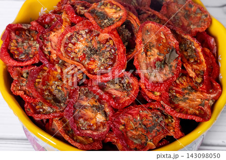 Bowl with dehydrated red fragrant tomatoes with herbs and spices. Bowl with dehydrated red fragrant tomatoes with herbs and spices. 143098050