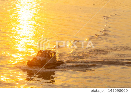 A small boat navigating through golden waters at sunset A small boat navigating through golden waters at sunset 143098060