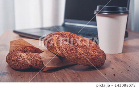 simits with coffee on a wooden table, with a laptop, in a cozy working environment, snack, breakfast, no people, 143098075