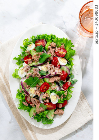 salad with canned tuna, cherry tomatoes, cucumber, and quail eggs on a white plate 143098083