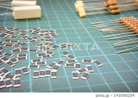 Electronic components scattered on cutting mat, resistors and SMD parts 143098284