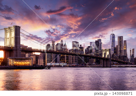 A panoramic sunset view of the Brooklyn Bridge stretching towards Manhattan 143098871