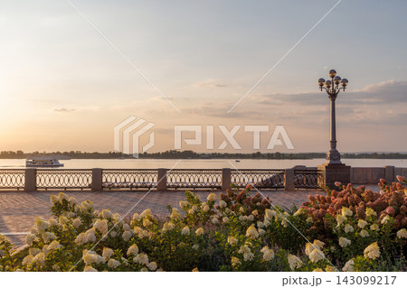 Beautiful riverside promenade with flowers at sunset Beautiful riverside promenade with flowers at sunset 143099217