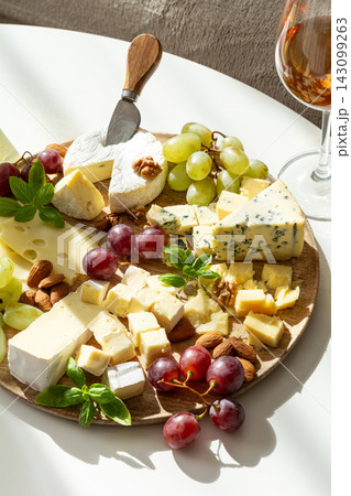 Assortment of gourmet cheeses with grapes nuts and a glass of rose wine Assortment of gourmet cheeses with grapes nuts and a glass of rose wine 143099263