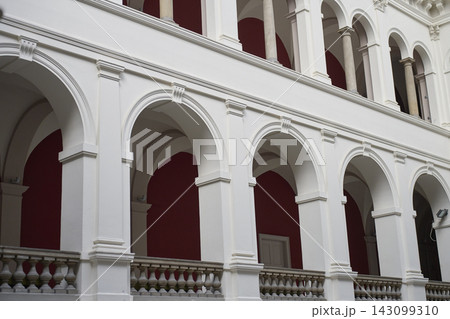 Rows of arches and columns frame red walls along interior gallery. Concept of classical architecture 143099310