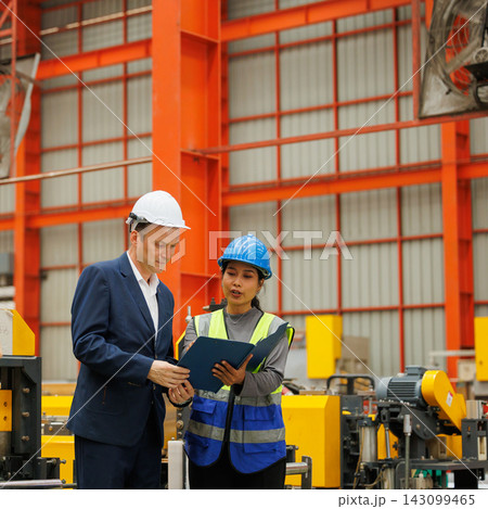 Factory Manager and Engineer Reviewing and Discussing Manufacturing Project Details in Factory. Factory Manager and Engineer Reviewing and Discussing Manufacturing Project Details in Factory. 143099465