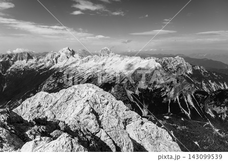 The image shows a view from the top of a mountain in Triglav National Park. The rocky terrain and surrounding peaks of the Julian Alps are visible under a clear sky during the day. The image shows a view from the top of a mountain in Triglav National Park. The rocky terrain and surrounding peaks of the Julian Alps are visible under a clear sky during the day. 143099539