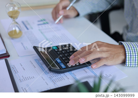 Businessman Calculating Financial Budget with Hourglass Clock on Desk. Time Management Concept. 143099999