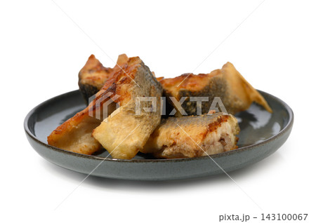 Commercial stock photo of pan-seared fish steak pieces on a dark plate, close-up side view Commercial stock photo of pan-seared fish steak pieces on a dark plate, close-up side view 143100067