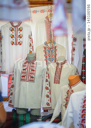 Traditional Embroidered Folk Shirts Displayed in Bulgaria. White traditional shirts decorated with red and multicolored folk embroidery are displayed on mannequins and hangers at craft stall 143100598