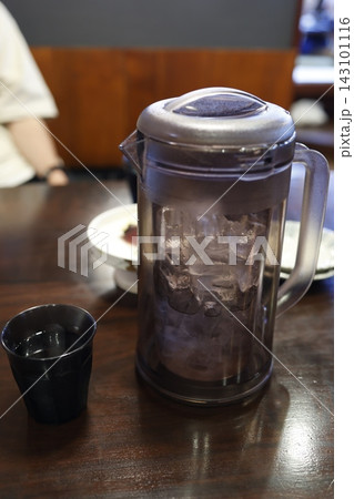 氷入りのお冷のピッチャーとコップ。飲食店の木製テーブル 143101116