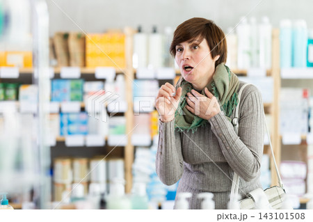 Woman suffering from severe cough in drugstore Woman suffering from severe cough in drugstore 143101508