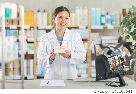 Young female pharmacist offering preparation in box Young female pharmacist offering preparation in box 143101541