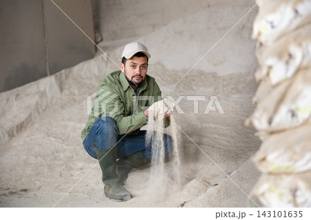 Portrait of farmer squatting at heap of corn flour 143101635