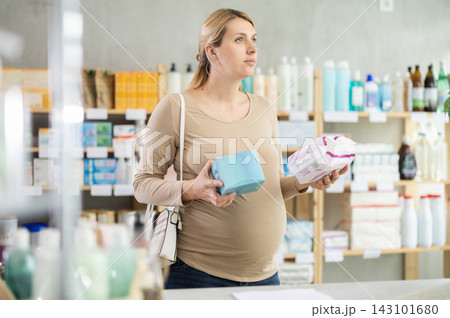 Pregnant woman in drugstore chooses woman pads Pregnant woman in drugstore chooses woman pads 143101680