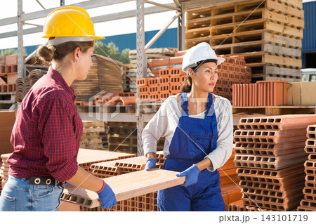 Women carrying flat hollow clay brick in outdoor warehouse Women carrying flat hollow clay brick in outdoor warehouse 143101719
