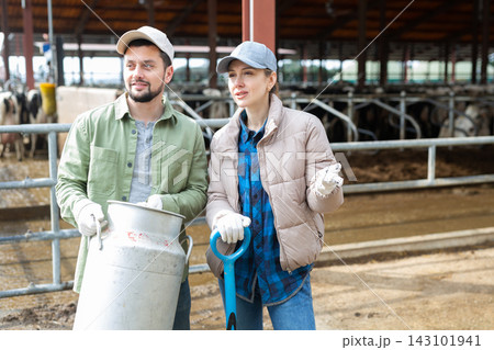 Man and woman dairy farm workers talking at cow barn Man and woman dairy farm workers talking at cow barn 143101941