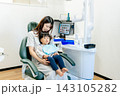 歯科医院の診察台で母親と2歳の子供の歯を診る歯科衛生士 143105282