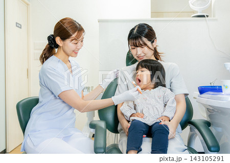 歯科医院の診察台で母親と2歳の子供の歯を診る歯科衛生士 歯科医院の診察台で母親と2歳の子供の歯を診る歯科衛生士 143105291