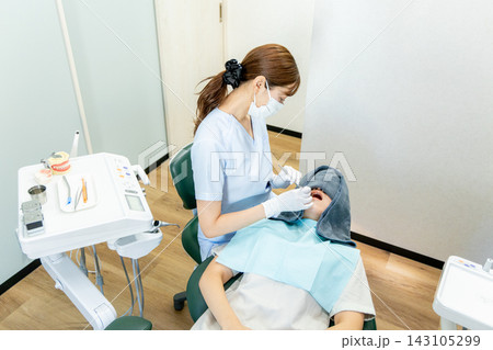歯科医院で治療を受ける女性患者と歯科医師 歯科医院で治療を受ける女性患者と歯科医師 143105299