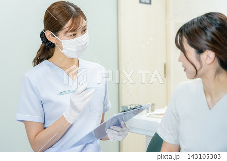 歯科医院で治療を受ける女性患者と歯科医師 歯科医院で治療を受ける女性患者と歯科医師 143105303
