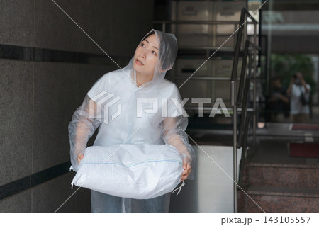 土のう袋を積んで水害対策をする女性 143105557