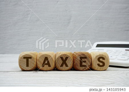TAXES alphabet letters with calculator on wooden background 143105943