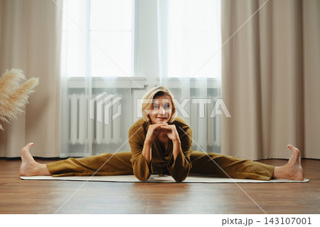 Yoga practice indoors during morning light with middle-aged woman stretching on mat in home setting 143107001