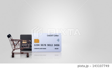 A close-up image of a miniature shopping cart next to two credit cards on a clean, light gray background, symbolizing e-commerce, banking, finance, and online shopping. Concept of Black Friday Sale 143107749