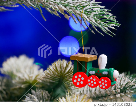 Wooden toy train hanging on frosted branch with bokeh Wooden toy train hanging on frosted branch with bokeh 143108023