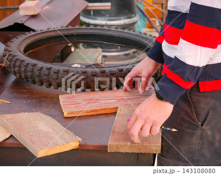 Hand marking wooden plank with pencil on workbench 143108080