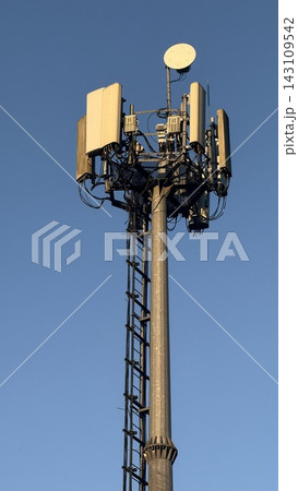 Close-up of tall telecommunication tower and 5G cellular antennas against a clear blue sky. 143109542