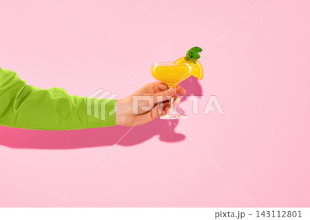 Hand holding orange cocktail on pink background with copy space. 143112801