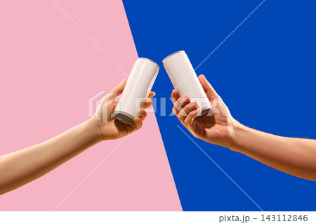 Two blank aluminum cans held in a toast gesture on pink and blue geometric background with premium copy space 143112846